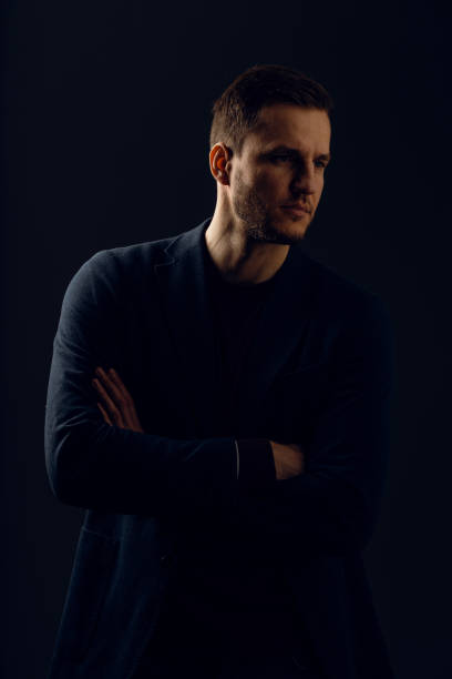 istock Business man portrait on dark background. Handsome young man weared suit in studio. Confident professional fashion male posing in studio. 1310128586