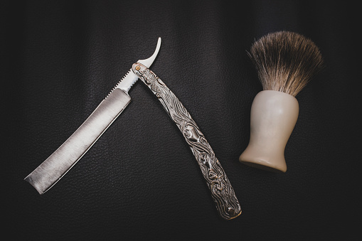 Close-up of shaving tools at a retro barber shop, over textured background. Grooming kit concepts.