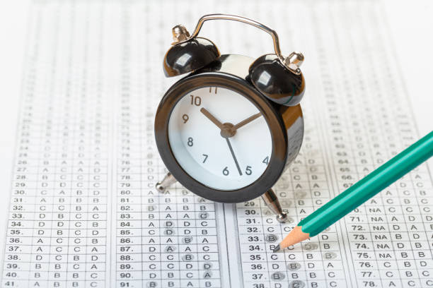 istock answer sheet, test in exercise and passing examination paper computer sheet with pencil alarm clock and pencil for education concept 1310131728