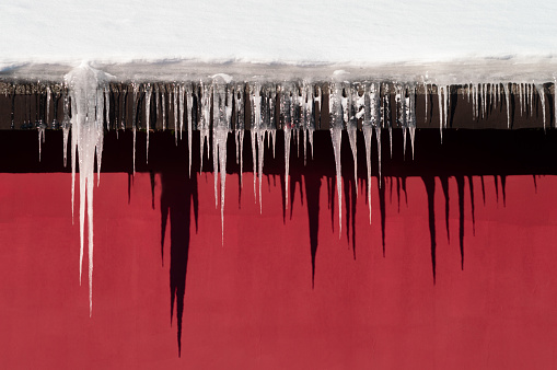 Background with icicles of different lengths casting shadows on the wall. High quality photo