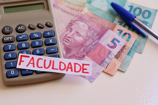 Faculdade (universidad) nota encima del dinero brasileño y calculadora. Costo de la matrícula universitaria en Brasil. photo