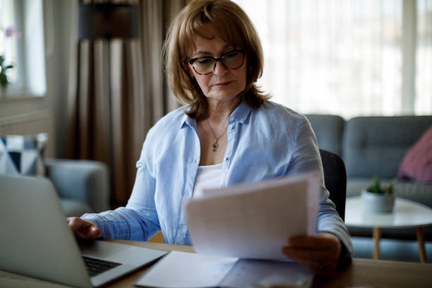 istock Serious mature woman using laptop for working at home 1310134647