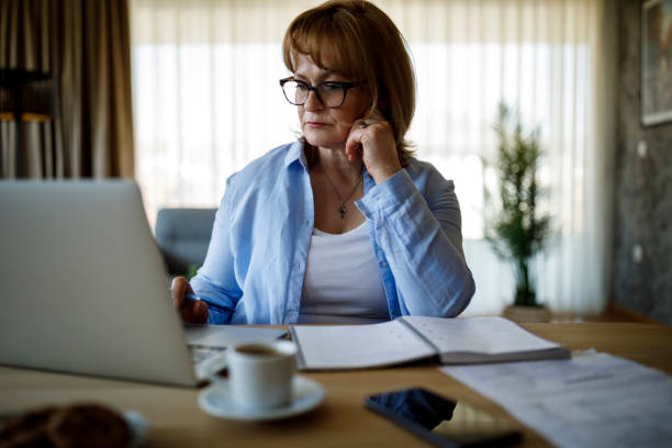 istock Serious mature woman using laptop for working at home 1310134675