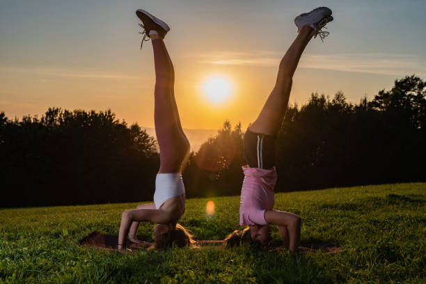 istock Two young women doing double yoga asana supported headstand. 1310140063