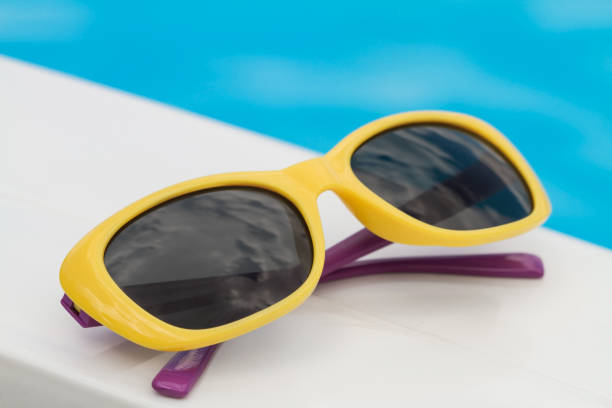 istock Children sunglasses lying on a deck-chair on blue water background 1310140550