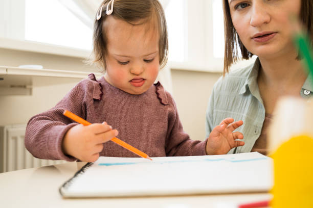 istock Kid with down syndrome drawing with pencil on paper while sitting at the table 1310140769