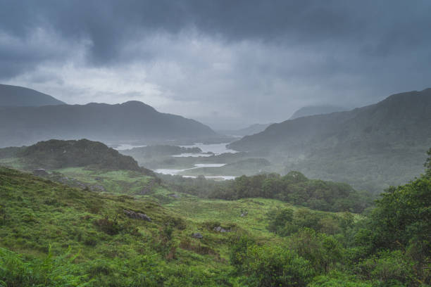 Dramatic storm sky, mist and heavy rain in Ladies View Atmospheric, dramatic storm sky and clouds, mist and heavy rain in Irish iconic viewpoint, Ladies View. Green valley with lake. Rink of Kerry, Ireland wilderness stock pictures, royalty-free photos & images