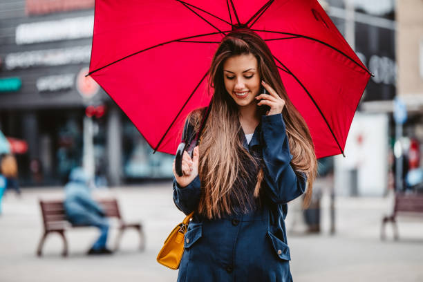istock Smiling woman talking on phone under umbrella 1310143225