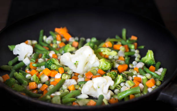 istock stewed vegetables (carrots, beans, peas, broccoli, cabbage, onions) lie in a black pan close-up 1310144375
