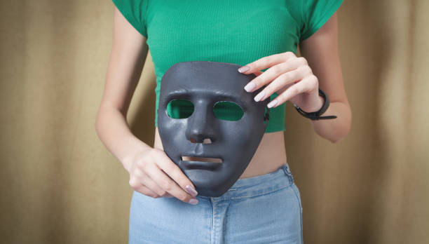 istock Young woman holding black mask. Fake, anonymous 1310145710