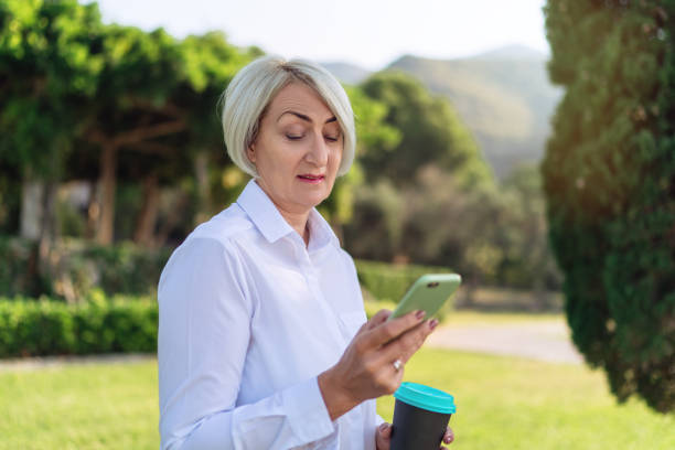 istock Mature woman using on mobile phone while resting at the park 1310146434