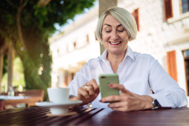 istock Mature woman using mobile phone while sitting at a cafe 1310146471