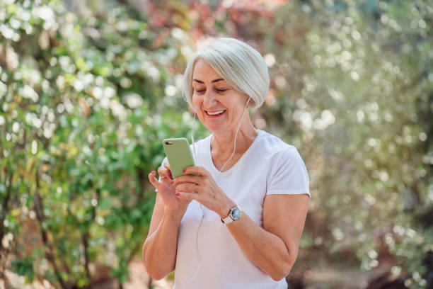 istock Senior woman runner in park using smartphone 1310147307