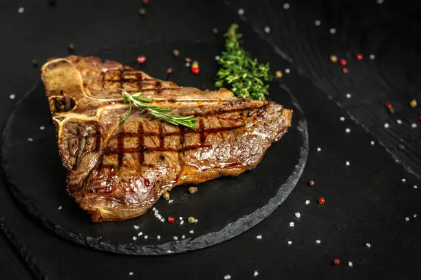Grilled BBQ T-Bone Steak or porterhouse steak with Fresh Rosemary. American cuisine. Restaurant menu, dieting, cookbook recipe. The concept of pral cooking meat.