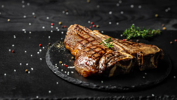 istock Grilled T-bone or aged wagyu porterhouse grilled beef steak on stone table. Long banner format, top view 1310148033