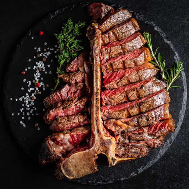 Barbecue Wagyu T-Bone Steak sliced. porterhouse grilled beef steak Medium rare on stone table. American meat restaurant. square image, top view