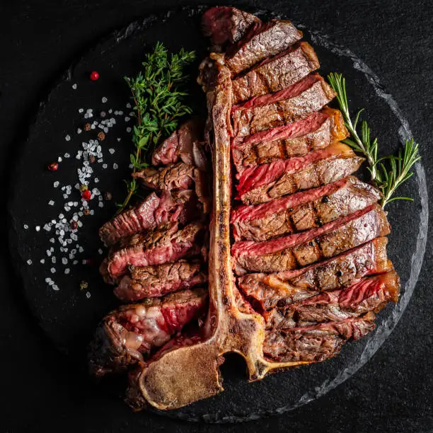 Photo of Barbecue Wagyu T-Bone Steak sliced. porterhouse grilled beef steak Medium rare on stone table. American meat restaurant. square image, top view