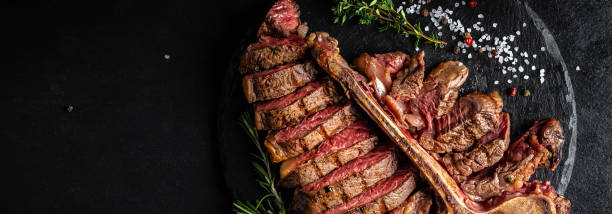 istock Beef T-Bone steak. Medium rare sliced grilled striploin beef steak with fork and knife. American meat restaurant. banner, catering menu recipe place for text 1310148042