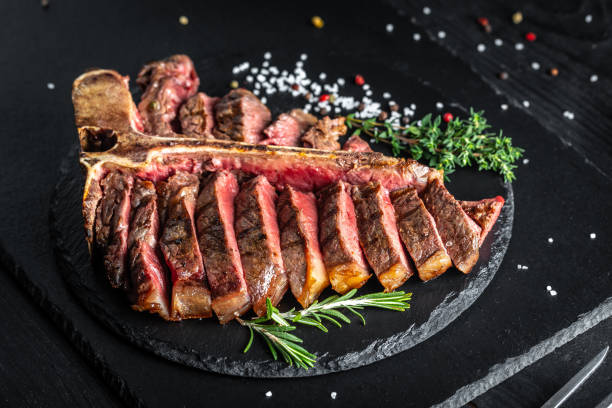 Barbecue dry aged Wagyu Porterhouse Steak sliced. Barbecue dry aged Wagyu Porterhouse Steak sliced with green Asparagus on a cutting board porterhouse steak stock pictures, royalty-free photos & images