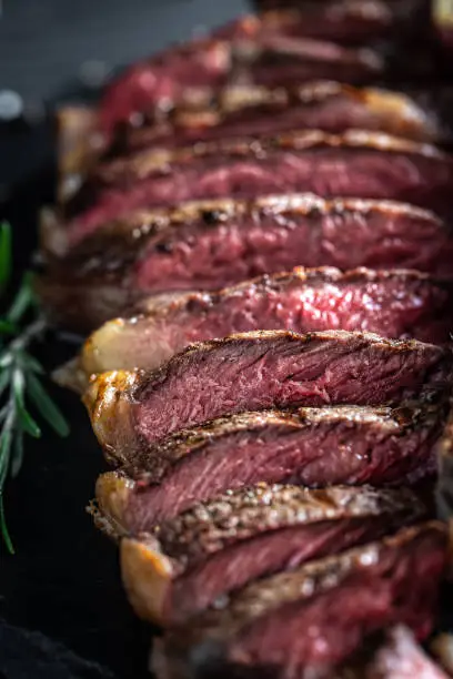 Barbecue dry aged wagyu porterhouse beef steak sliced with large fillet piece. Food recipe background. Close up. vertical image.