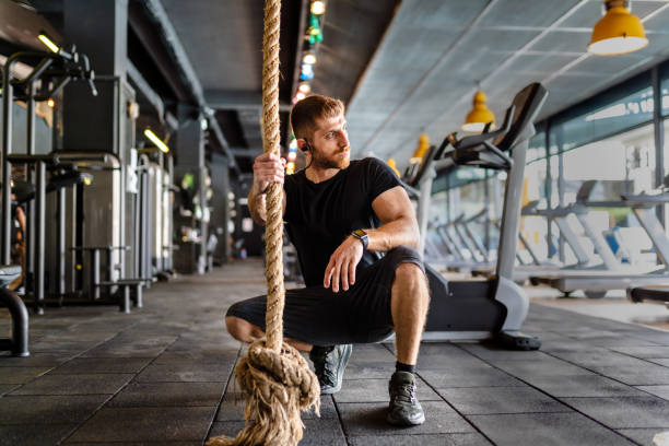 istock Young athletic man exercising strength on a rope in a gym. 1310155248