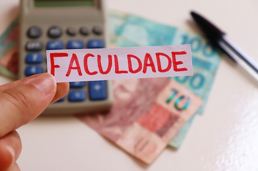 Nota de Faculdade (universidad) con dinero brasileño y calculadora en segundo plano. Costo de la matrícula universitaria en Brasil. photo