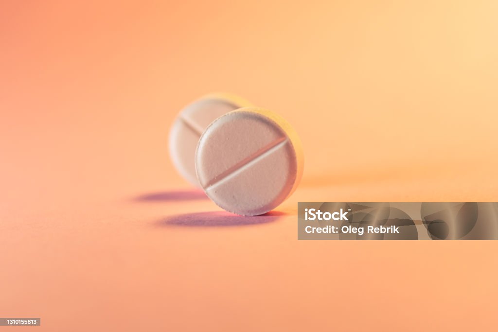 Dos pastillas en un fondo rosa anaranjado. Tema médico. Enfoque selectivo. - Foto de stock de Aborto libre de derechos