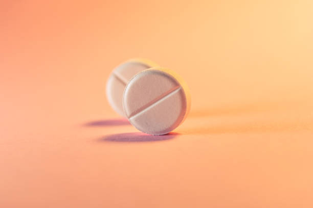 two pills in an orange-pink background. medical theme. selective focus. - birth control pill imagens e fotografias de stock