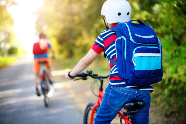 Children with rucksacks riding on bikes in the park near school. Children with rucksacks riding on bikes in the park near school. Pupils with backpacks outdoors. bicycle cycling school child stock pictures, royalty-free photos & images