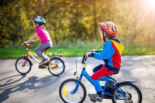 Cute children riding on bicycles on asphalt road in summer. Concept of friendship between people.