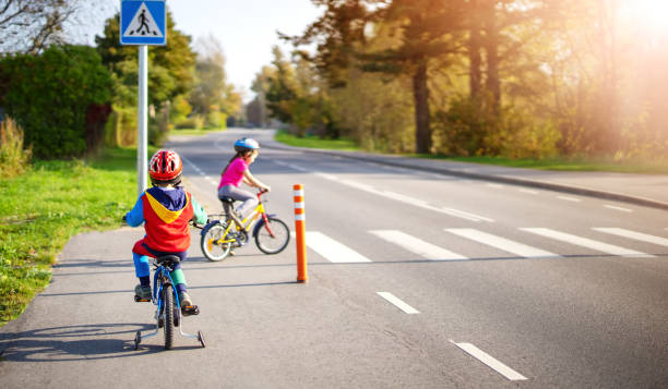 lindos niños montando en bicicletas en la carretera de asfalto en verano. - familia de cruzar la calle fotografías e imágenes de stock