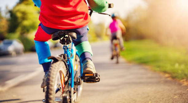 cute children riding on bicycles on asphalt road in summer. - child bicycle cycling danger imagens e fotografias de stock