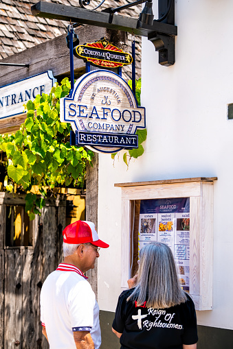 St. Augustine, USA - May 10, 2018: People senior couple standing outside outdoors reading menu by Seafood Company restaurant sign in Florida city on St George Street