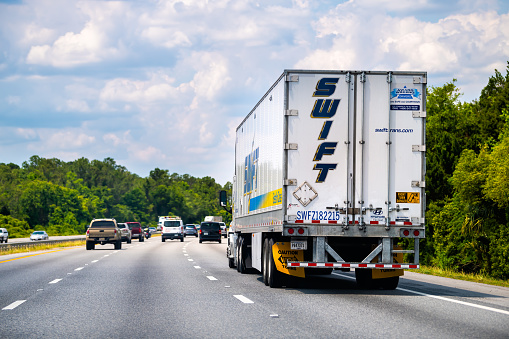 Yulee, USA - May 10, 2018: Swift Transportation truck carrier on interstate multiple lane highway in Florida carrying cargo freight commercial container on rural countryside road