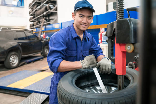 młody mechanik samochodowy wyważanie koła - trainee auto repair shop computer manual worker zdjęcia i obrazy z banku zdjęć