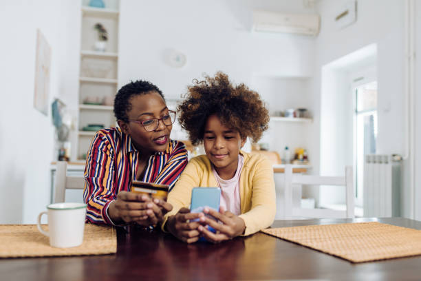 donna anziana afroamericana e sua nipote che fanno un acquisto online a casa - wireless technology cheerful granddaughter grandmother foto e immagini stock
