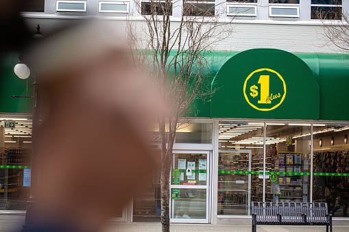 Victoria, Canada - March 25, 2021. A dollarstore on one of the main roads in Victoria BC. A blurred hand holds a coffee cup in the foreground.