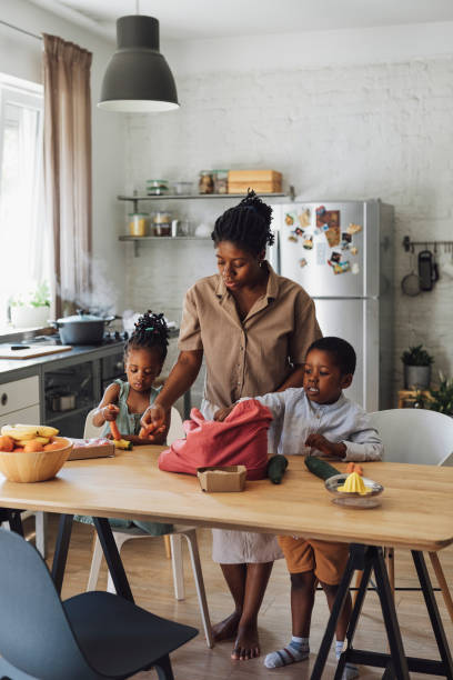 istock Mother, Daughter and Son Preparing Vegetables for Lunch at a Kitchen Table 1310168649
