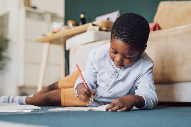 istock Young Boy Using Colour Pencils Drawing on the Floor and Smiling 1310168695