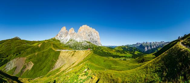 Aerial view of Italian alps in a sunny cloudless day - Langkofel (The Saslonch, Sassolungo) mountains, surrounded by green meadows. High resolution panorama.