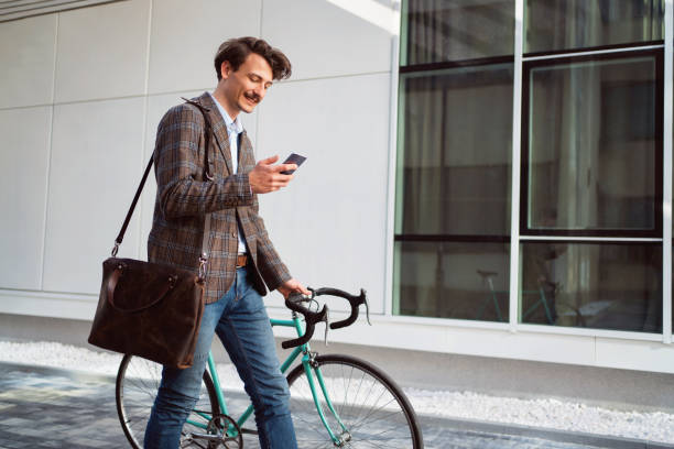 istock Side view of a young modern man using the smartphone while walking with a bike 1310168891