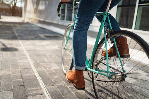 Close-up of an unrecognizable man in leather shoes riding his bike on the way to work.