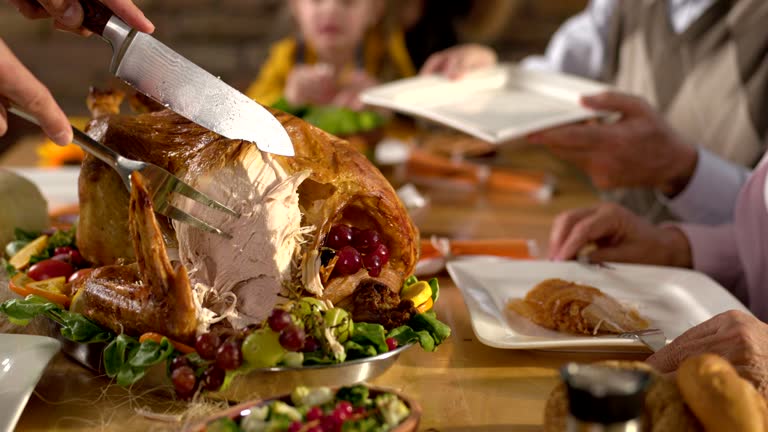 Close up of unrecognizable man carving roasted Thanksgiving turkey.