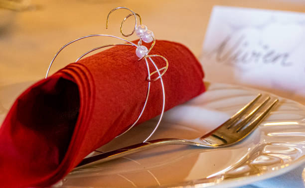 istock Table setting with white dishes and red napkin roll on a white tablecloth. Decoration for wedding or birthday Copy space 1310171794