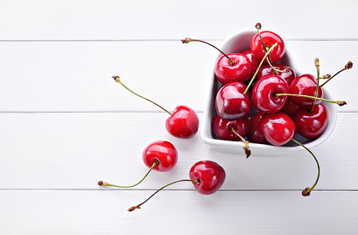 Ripe cherries on white table, space for text.