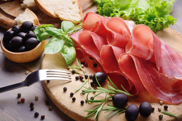 Italian snack with raw ham, bread, olives, lattuce and herbs on cutting board. Serrano ham, close-up. parma ham stock pictures, royalty-free photos & images