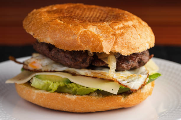 Homemade burger with lettuce, cheese, and egg.