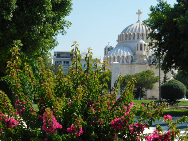 A blooming bougainvillea with pink flowers, and a church, in Glyfada, Greece