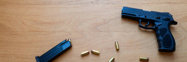 istock firearm, 40 caliber pistol in ammunition on wooden surface. 1310178216