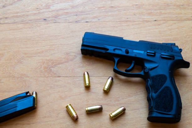 istock firearm, 40 caliber pistol in ammunition on wooden surface. 1310178218